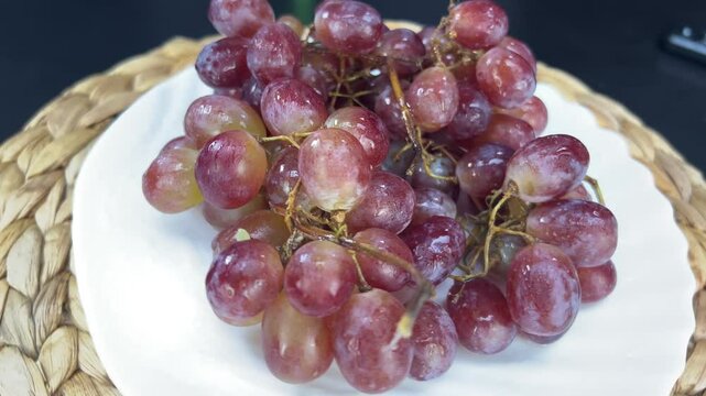 Rotating bunch of vibrant red grapes on a decorative plate