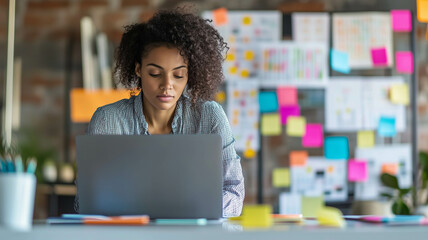 A focused project coordinator in a modern office, intently reviewing timelines on a laptop