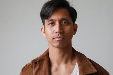 Obraz premium Portrait of serious asian man posing over white background looking at the camera.