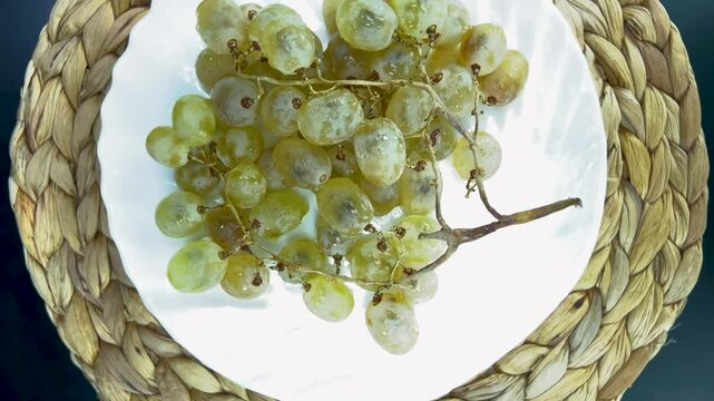 Rotating bunch of vibrant green grapes on a decorative plate