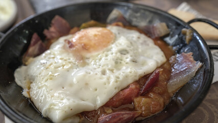 Revuelto de jamón , pisto de verduras y huevo frito servido en cazuela