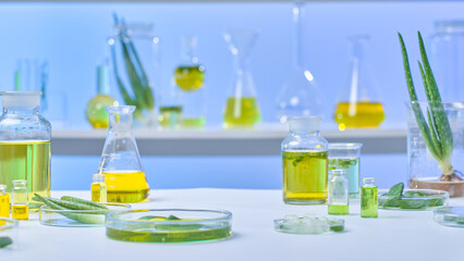 A photographic of a contemporary lab setting, complete with all the equipment needed, including a beaker, cork bottle, petri dish, flask, small bottle, aloe, and several solutions for aloe research.