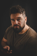 Fototapeta premium Portrait of a middle age man using a phone isolated on the black background.
