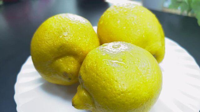 Three wet lemons rotating on a white plate