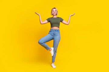 Full size photo of nice girl dressed crop top hold balance on one leg arms hold objects empty space isolated on yellow color background