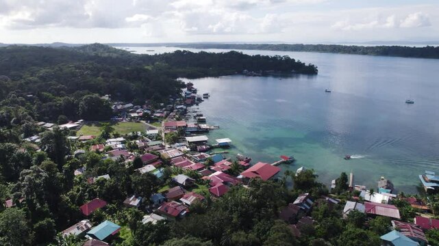 Aerial panoramic establishing view of homes along Bastimentos Island's coastline in Bocas del Toro, Panama