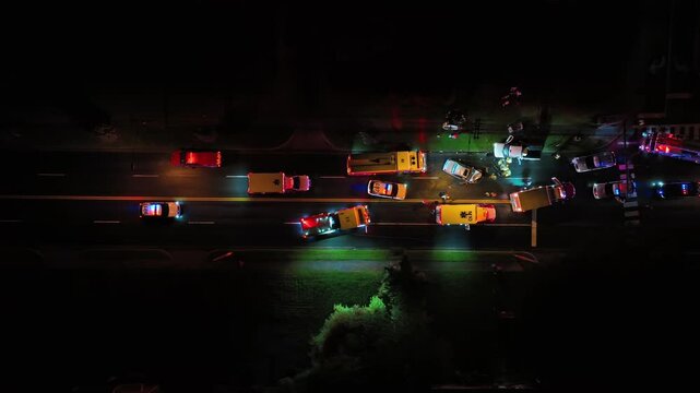 Aerial top down of car accident on road at night. Fire Truck, Police Car and Ambulance on street. American suburb district in Virginia, USA.