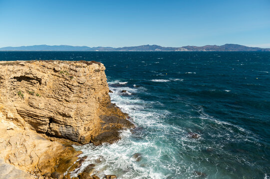 imagen de un acantilado en la costa del mediterr&aacute;neo, des del pueblo de l'Escala, con el cielo azul y el mar con olas 