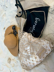 Beach bags with Boracay inscriptions, straw hat and sunglasses on the sand