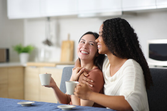 Happy interracial lesbian couple in love looking each other