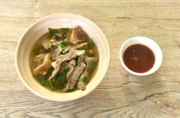 boiled braised beef meat and tendon in herb brown soup on bowl dipping spicy chili sauce 