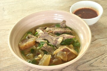 boiled braised beef meat and tendon in herb brown soup on bowl dipping spicy chili sauce 