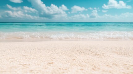 Obraz premium A serene beach scene with clear turquoise waves gently hitting the shore under a bright blue sky with scattered clouds, capturing a sense of peace and relaxation.