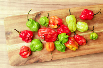 Hot Colourful Chilli Peppers on wooden cutting board. Vivid colour close up photograph. Flat lay view.
