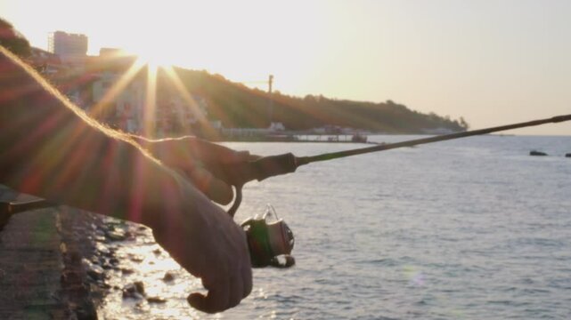 Man fishing at sea with spinning reel against calm ocean