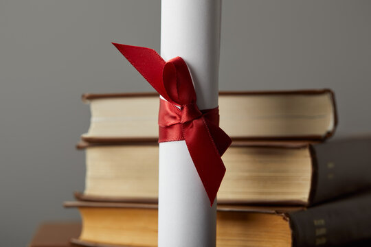 A diploma with a red ribbon lies beside vintage books, symbolizing the quest for knowledge and learning.