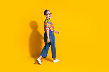 Photo of lovely adorable woman wear trendy print clothes walk empty space isolated on vibrant yellow color background