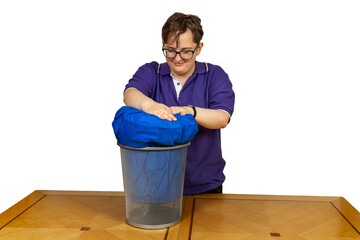 Young student stuffs blue sleeping bag into waster paper trash can bin ready for going back to college university, isolated on white background