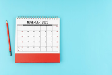 November desk calendar for 2025 year with pencil on blue background, Position with copy space.