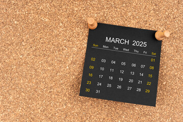 Black calendar sheet for March 2025 with thumbtack on wooden board, Position with copy space.