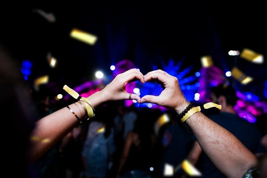 Couple making heart symbol shape with their hands at festival