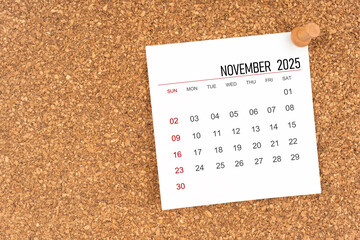 White calendar sheet for November 2025 with thumbtack on wooden board, Position with copy space.