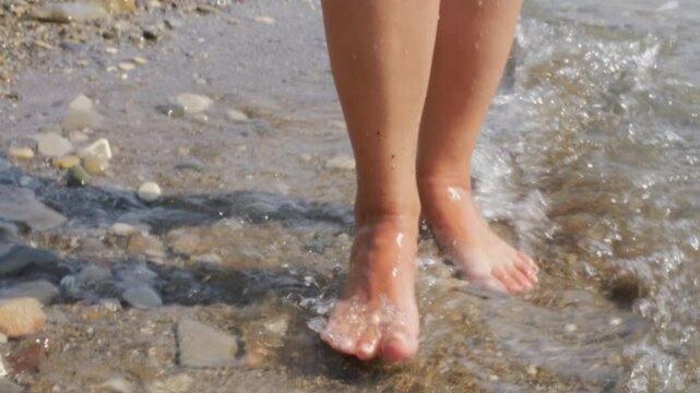 Feet of woman walking on pebble beach