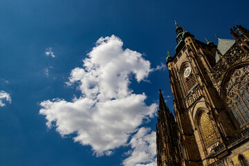 Glimpse, seen from below, of St. Vitus Cathedral in Prague, in the background blue sky and white clouds.