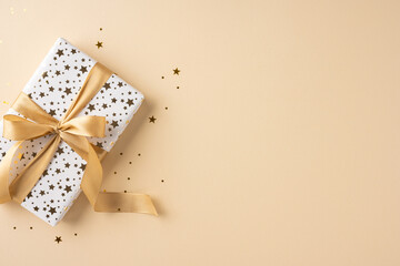 Beautifully wrapped gift with a golden ribbon and star pattern, perfect for festive Christmas and New Year celebrations on a soft beige background
