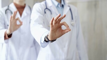 Two doctors is showing ok sign with fingers while standing in a hospital. Teamwork and success in medicine