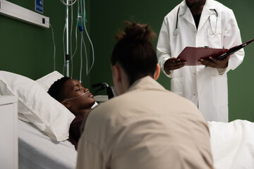 African doctor stands with a folder of medical records, ready to discuss the ongoing treatment plan...