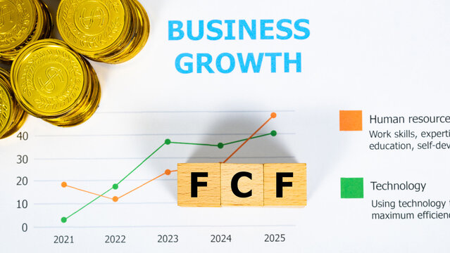 Three wooden blocks with the word FCF on a graph sheet with a pile of gold coins. Abbreviation for Free Cash Flow, growth business and investment. Business and financial market concept.