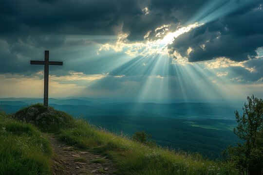 A cross on a hilltop with rays of sunlight breaking through the clouds, illuminating the landscape.