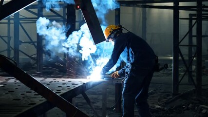 Welder working with intense sparks in a factory setting, wearing protective gear