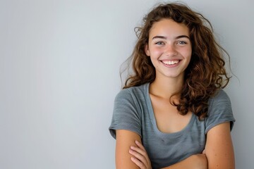 Obraz premium Young woman with a cheerful expression and folded arms, white background , background blur