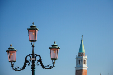 Vintage street lamp and bell tower under blue sky in Venice Italy