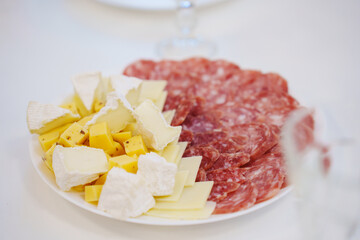 plate with sausage and cheese slices. A traditional appetizer for a banquet.