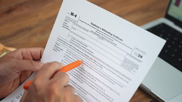 Office worker indicates important information on W-4 tax form with pen reviewing document thoroughly to make informed decisions about tax withholdings slow motion