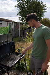A white European man makes a barbecue in the garden. Grilling in the home garden. Grill cleaning