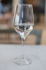 A wine glass is filled with water and stands on the table