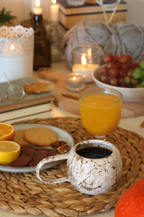 Pumpkins, various food and drinks, fall decorations, books and candles on the table. Fall hygge at home. Selective focus.