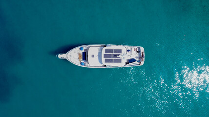 Aerial view from above of a large eco-friendly yacht with solar panels receiving energy during the day in the sea with clear, blue water. In the Mediterranean Sea.
View from drone.