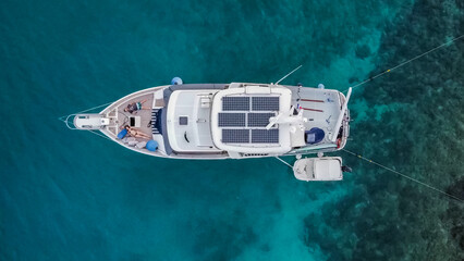 Aerial view from above of a large eco-friendly yacht with solar panels receiving energy during the...