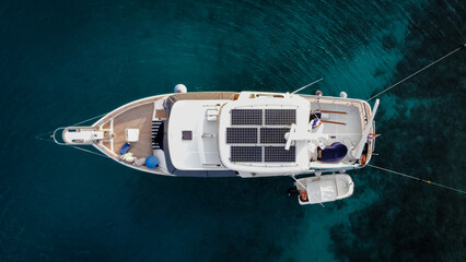 Aerial view from above of a large eco-friendly yacht with solar panels receiving energy during the...
