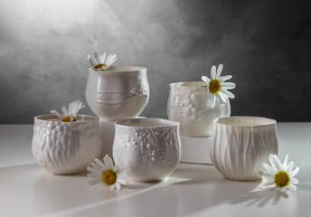 Porcelain white cups with chamomile flowers on a light table