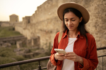 Happy hispanic woman using phone in ancient fortress or castle. Lifestyle, travel, tourism and...