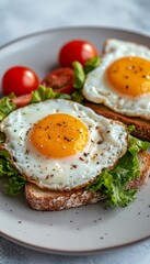 Two Delicious Open-Faced Fried Egg Sandwiches, Fresh Lettuce, and Juicy Tomatoes on a Plate