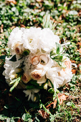 Bridal bouquet and two rings, on the grass under a veil