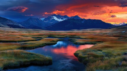   A river runs through a green field beneath pink-orange clouds, framed by mountains