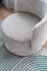 Cozy modern accent chair placed on a striped rug in a bright living room